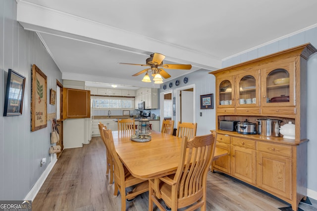 dining area featuring beamed ceiling, ceiling fan, ornamental molding, and light hardwood / wood-style floors