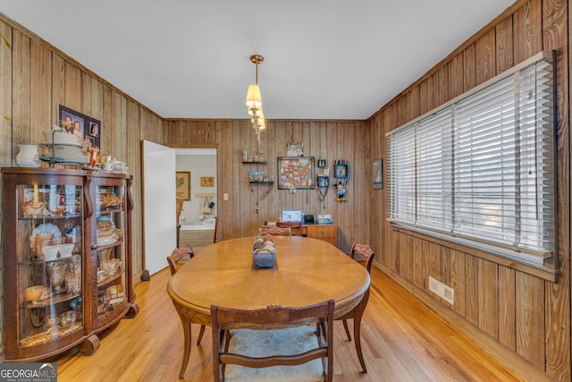 dining space with light hardwood / wood-style floors and wood walls