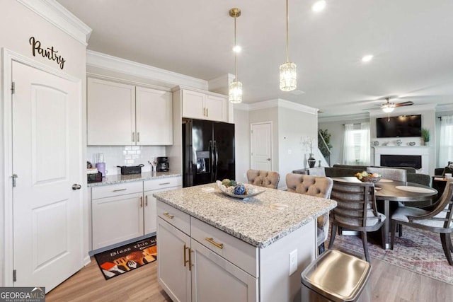 kitchen featuring pendant lighting, a center island, backsplash, light wood-type flooring, and black fridge with ice dispenser