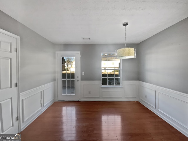 unfurnished dining area featuring a textured ceiling and dark hardwood / wood-style flooring