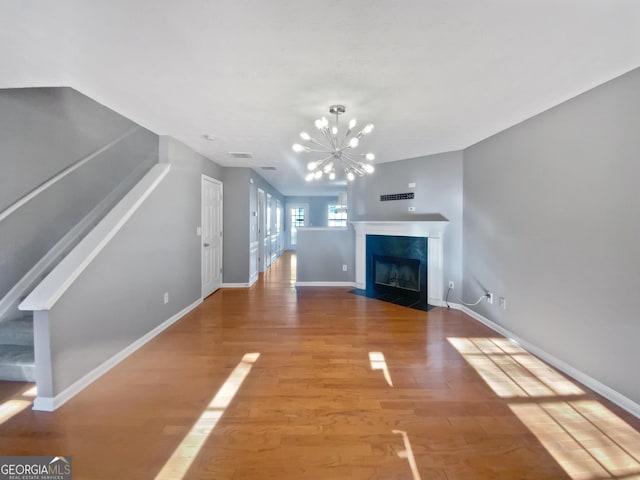 unfurnished living room with a chandelier and wood-type flooring