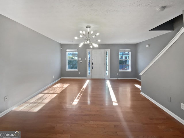 entrance foyer featuring a textured ceiling, hardwood / wood-style floors, and a chandelier