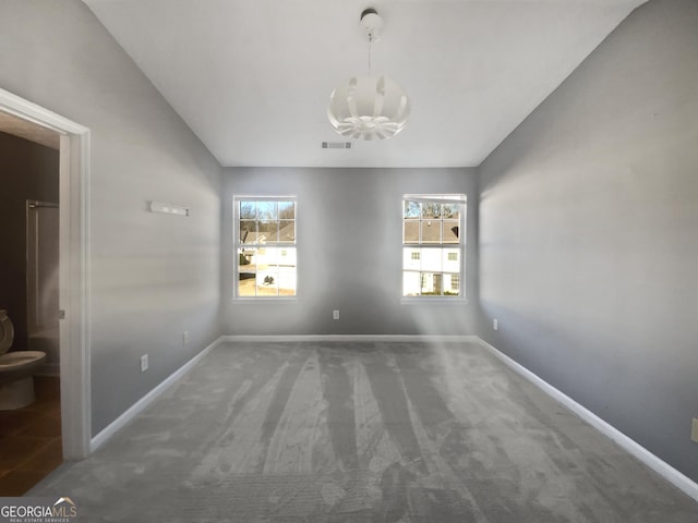 unfurnished dining area with vaulted ceiling, dark carpet, and an inviting chandelier