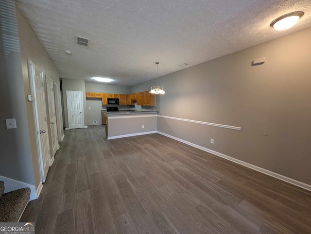 kitchen featuring dark wood-type flooring, hanging light fixtures, a textured ceiling, and an inviting chandelier