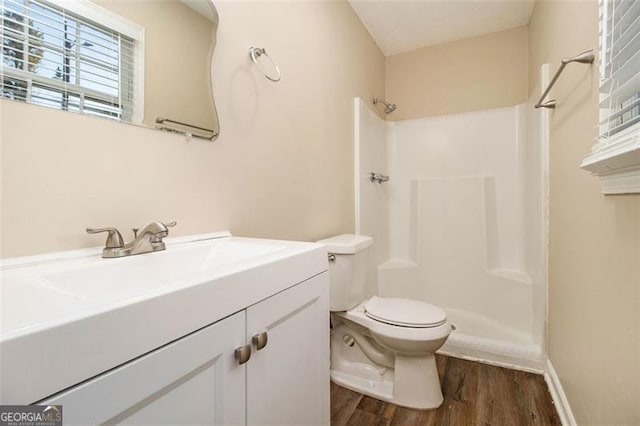 bathroom featuring toilet, vanity, a shower, and hardwood / wood-style floors