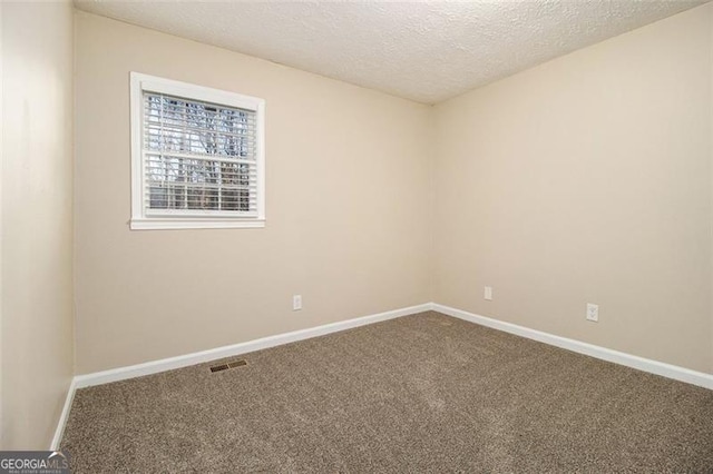 unfurnished room featuring a textured ceiling and carpet