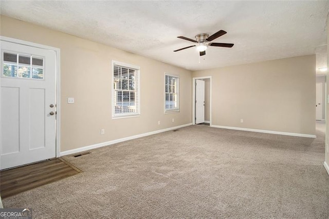 carpeted foyer with ceiling fan and a textured ceiling