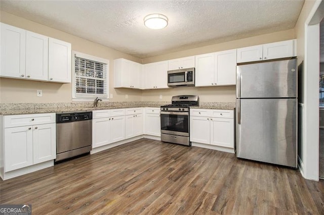 kitchen featuring a textured ceiling, appliances with stainless steel finishes, dark hardwood / wood-style flooring, and white cabinets