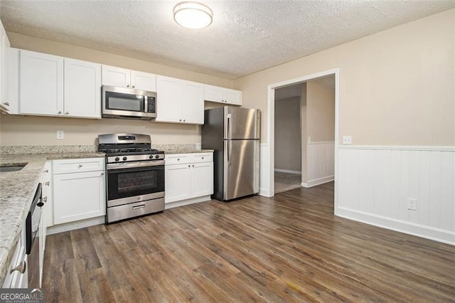 kitchen with dark hardwood / wood-style flooring, stainless steel appliances, and white cabinetry