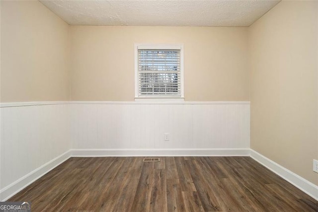 empty room with a textured ceiling and dark hardwood / wood-style floors