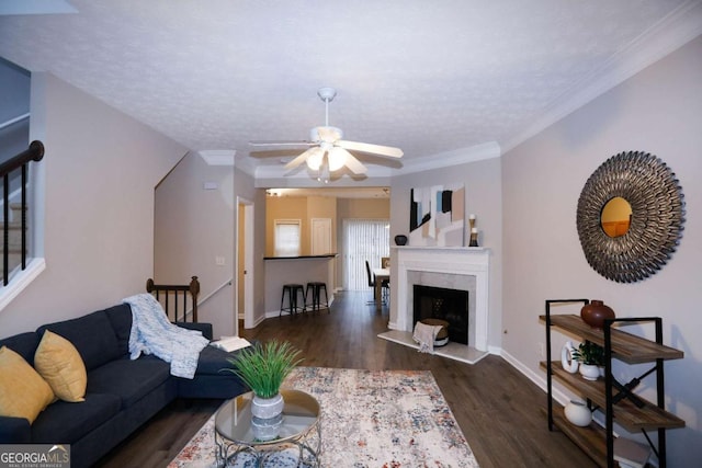 living area with baseboards, ornamental molding, wood finished floors, a textured ceiling, and a fireplace