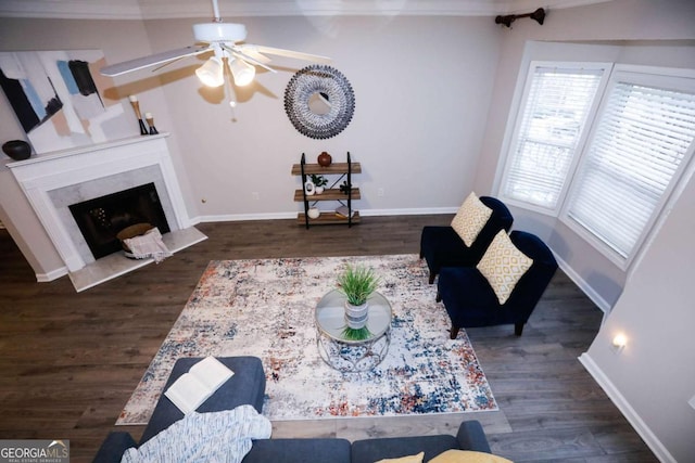 living room featuring ceiling fan, dark wood-type flooring, ornamental molding, and a fireplace