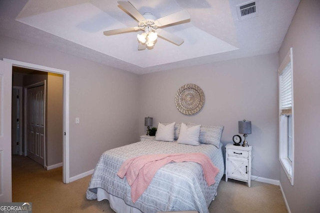 bedroom featuring ceiling fan, carpet flooring, and a raised ceiling