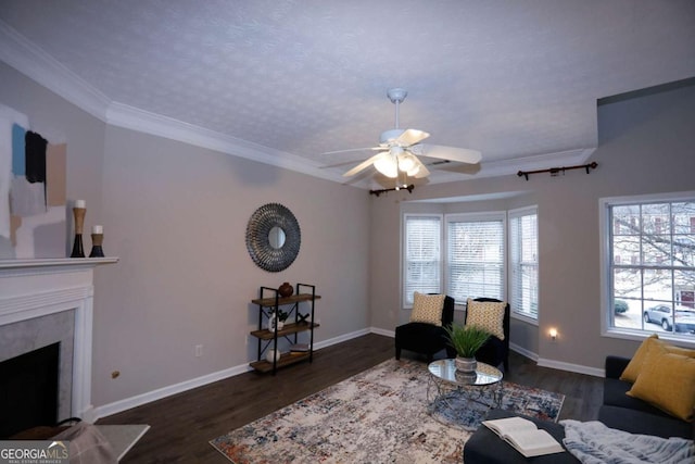 living room featuring ceiling fan, dark hardwood / wood-style flooring, a fireplace, a textured ceiling, and crown molding