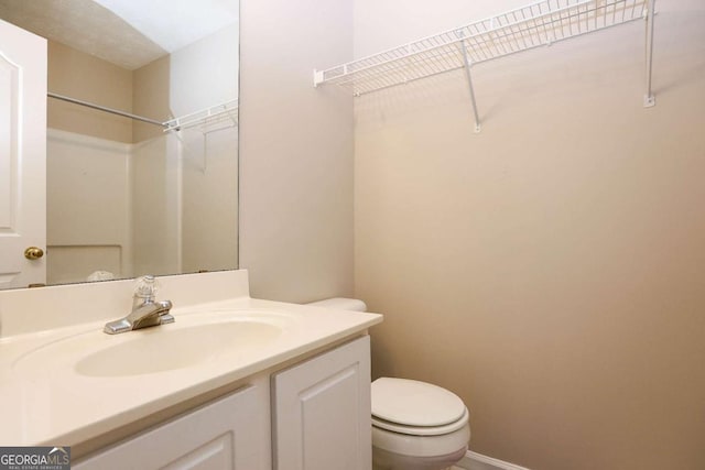 bathroom featuring toilet, baseboards, and vanity