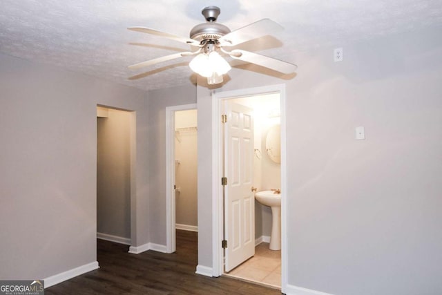 unfurnished bedroom featuring ceiling fan, ensuite bath, wood-type flooring, a textured ceiling, and a closet