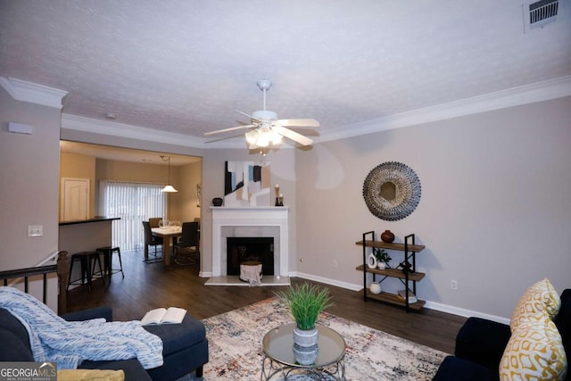 living room featuring a textured ceiling, dark wood-type flooring, ornamental molding, and ceiling fan