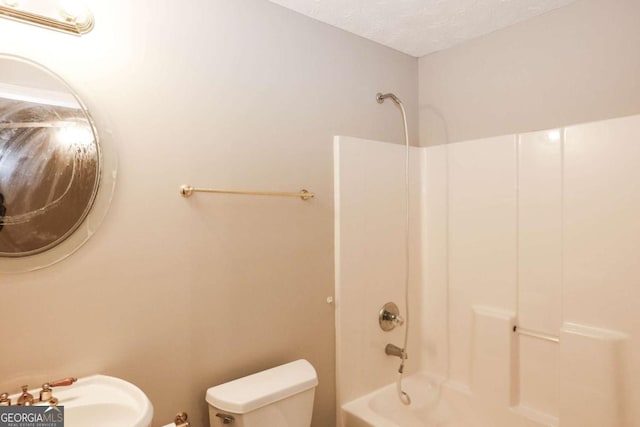 full bathroom with sink, bathtub / shower combination, toilet, and a textured ceiling