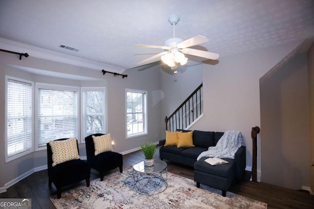 living room featuring wood finished floors, visible vents, baseboards, stairs, and ornamental molding