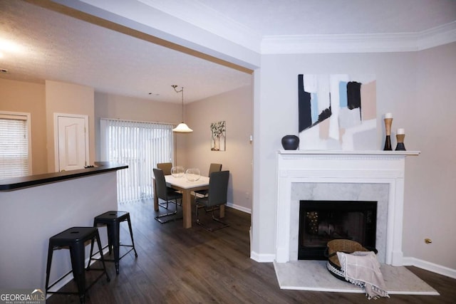 living room with a healthy amount of sunlight, dark wood-type flooring, a premium fireplace, and crown molding