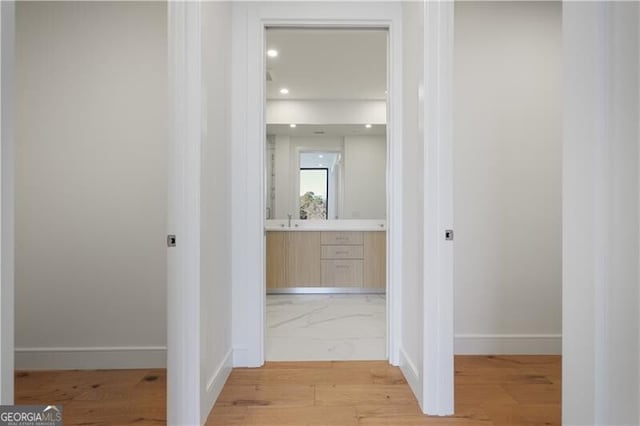 hallway with sink and light hardwood / wood-style flooring