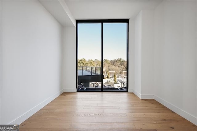 unfurnished room featuring light hardwood / wood-style floors and a wall of windows