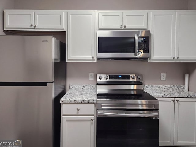 kitchen featuring stainless steel appliances, white cabinets, and light stone countertops