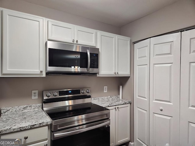 kitchen featuring light stone counters, white cabinets, and stainless steel appliances