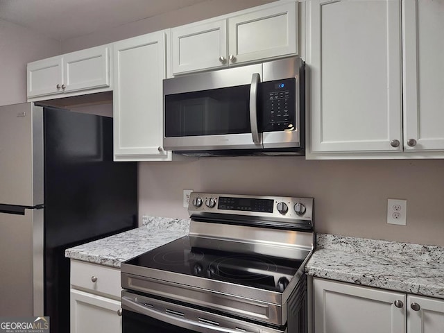 kitchen featuring appliances with stainless steel finishes, white cabinetry, and light stone counters