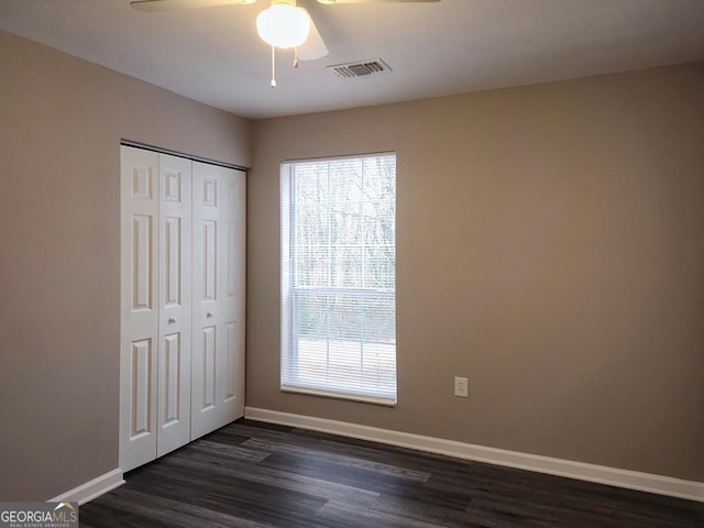 unfurnished bedroom with ceiling fan, a closet, and dark hardwood / wood-style floors