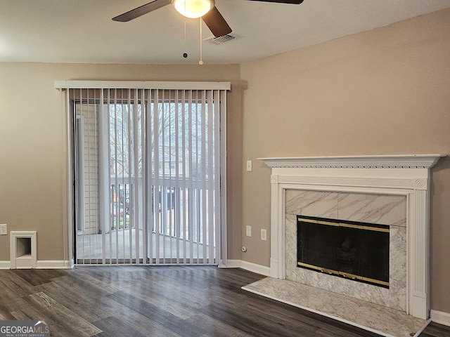 unfurnished living room featuring dark wood-type flooring, a premium fireplace, and ceiling fan