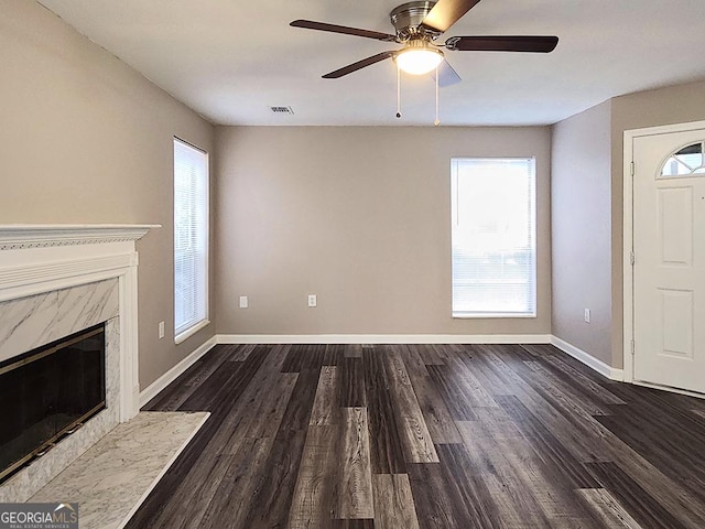 unfurnished living room featuring a premium fireplace, dark hardwood / wood-style floors, and ceiling fan