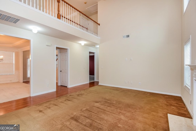 unfurnished living room with carpet flooring, a chandelier, and a high ceiling