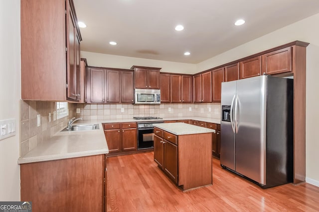 kitchen with light wood-type flooring, appliances with stainless steel finishes, sink, and a kitchen island