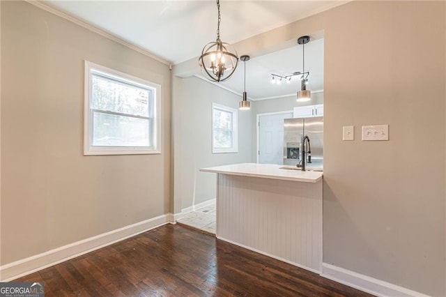 interior space featuring dark wood-type flooring, sink, crown molding, stainless steel fridge with ice dispenser, and pendant lighting