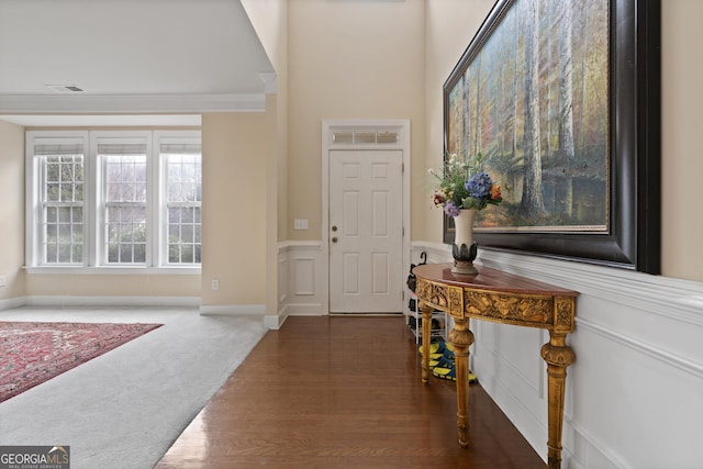 carpeted foyer featuring crown molding