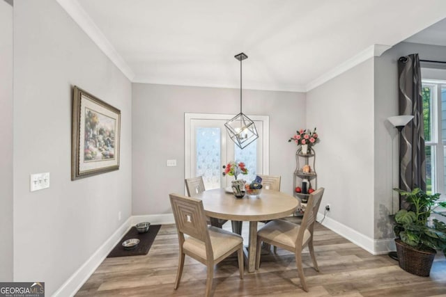 dining space featuring light wood-type flooring, an inviting chandelier, and ornamental molding