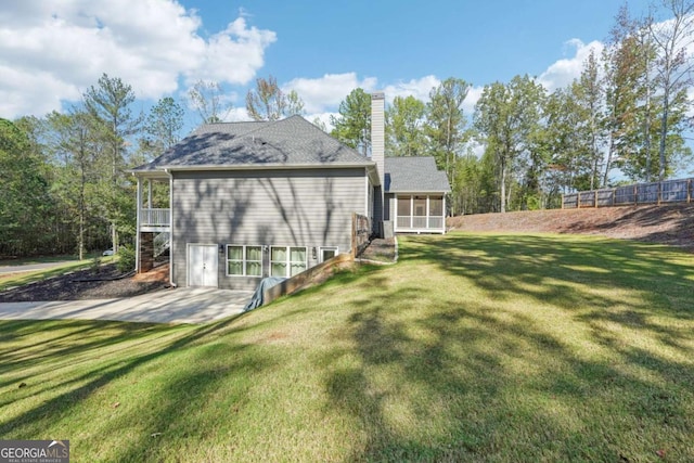 back of property with a lawn, a patio area, and a sunroom