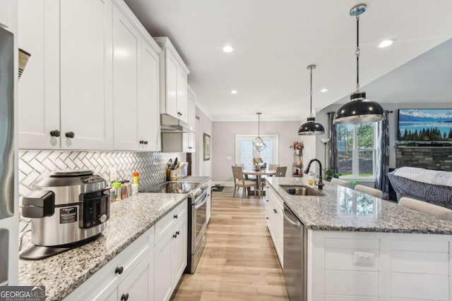 kitchen featuring sink, white cabinetry, a kitchen island with sink, stainless steel appliances, and light stone counters