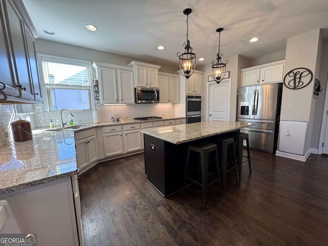 kitchen featuring a center island, hanging light fixtures, appliances with stainless steel finishes, white cabinets, and dark hardwood / wood-style flooring