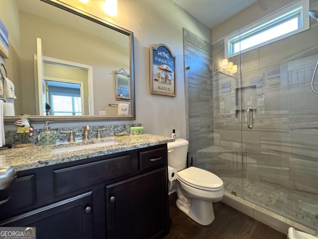 bathroom with toilet, a shower with shower door, hardwood / wood-style flooring, and vanity