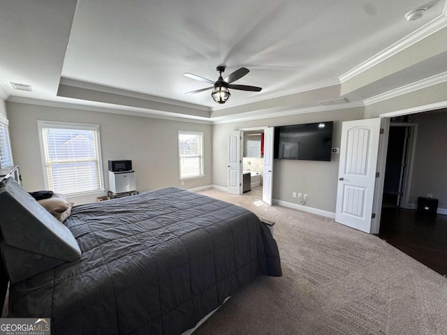 carpeted bedroom with ceiling fan, multiple windows, crown molding, and a raised ceiling