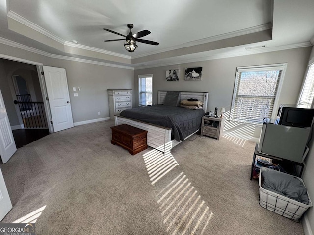 bedroom featuring ceiling fan, multiple windows, a raised ceiling, and carpet flooring