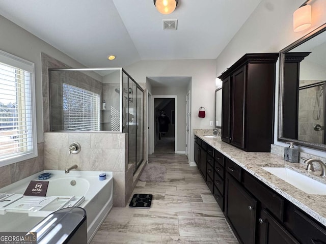 bathroom featuring lofted ceiling, vanity, and independent shower and bath