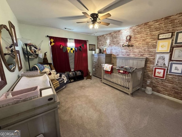 carpeted bedroom with ceiling fan, brick wall, and a crib