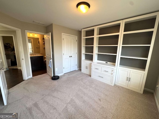 unfurnished bedroom featuring light carpet and connected bathroom