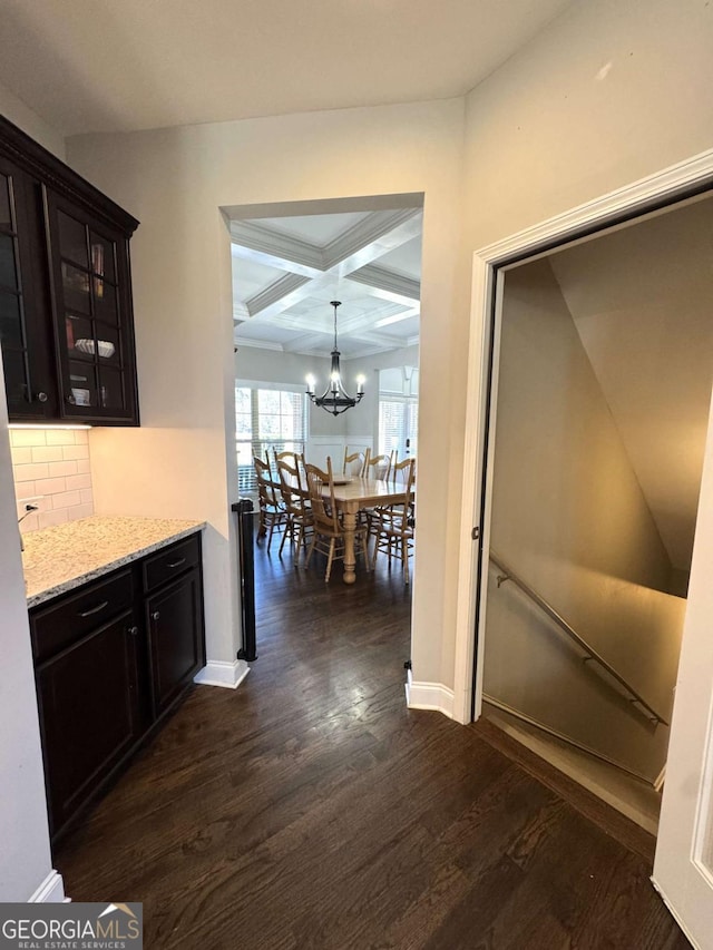 corridor featuring a chandelier, dark hardwood / wood-style flooring, beamed ceiling, and coffered ceiling