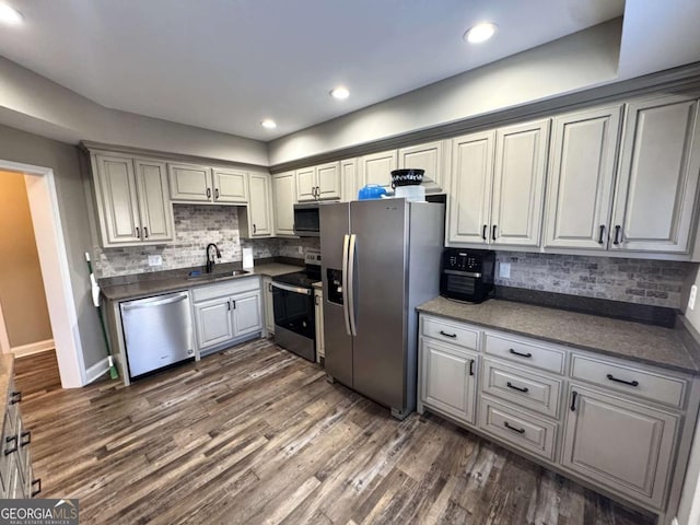 kitchen with appliances with stainless steel finishes, dark hardwood / wood-style floors, tasteful backsplash, and sink