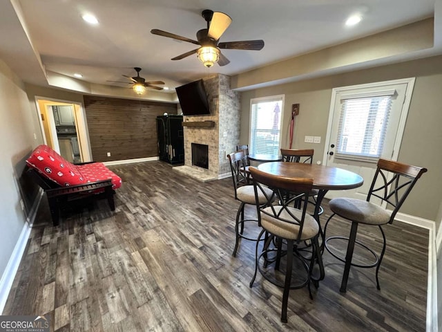 dining space with wood-type flooring, a fireplace, and a tray ceiling