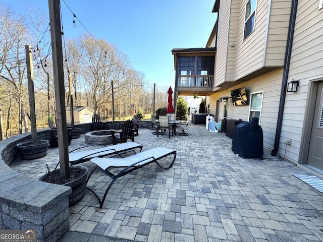 view of patio with an outdoor fire pit and a balcony